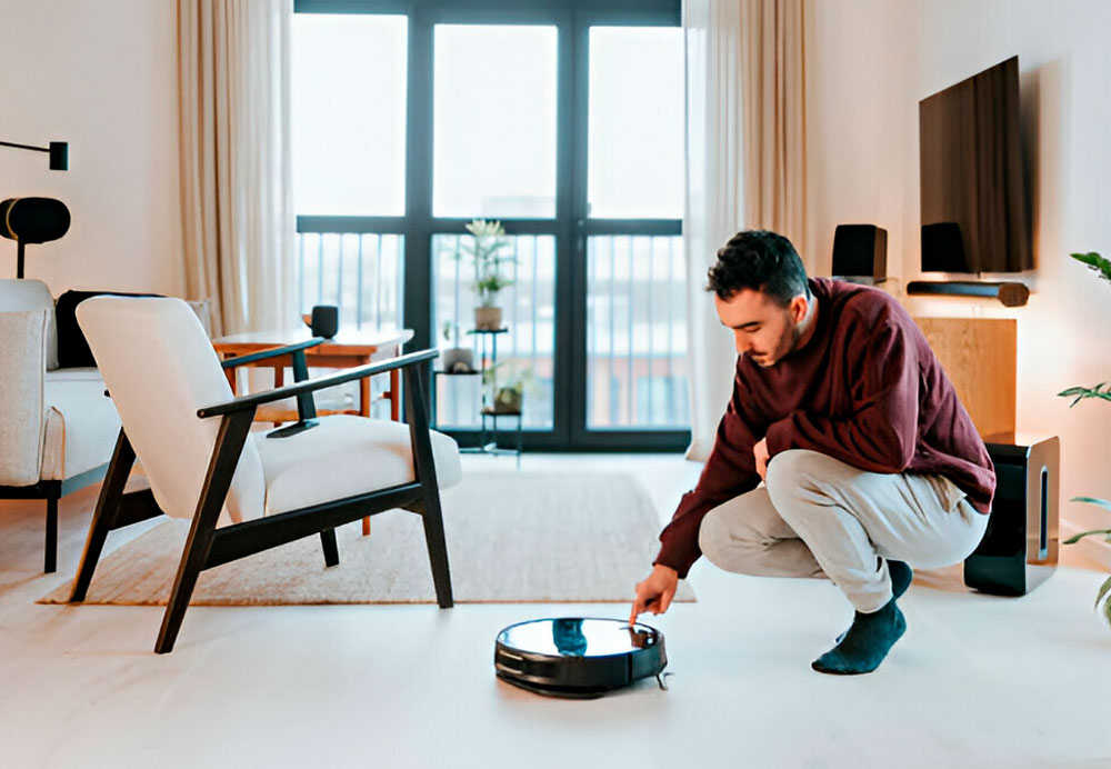 hombre encendiendo un robot aspiradora